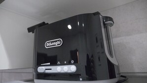 En DeLonghi toaster med et sort-hvidt design, komplet med digitalt display og flere betjeningsknapper.