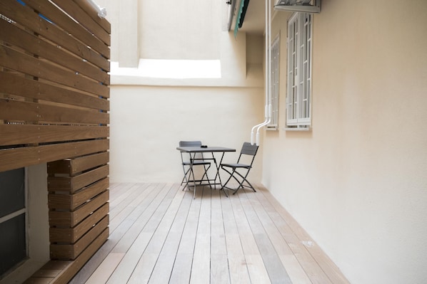 A small, enclosed patio area with a wooden bench and a table with chairs.