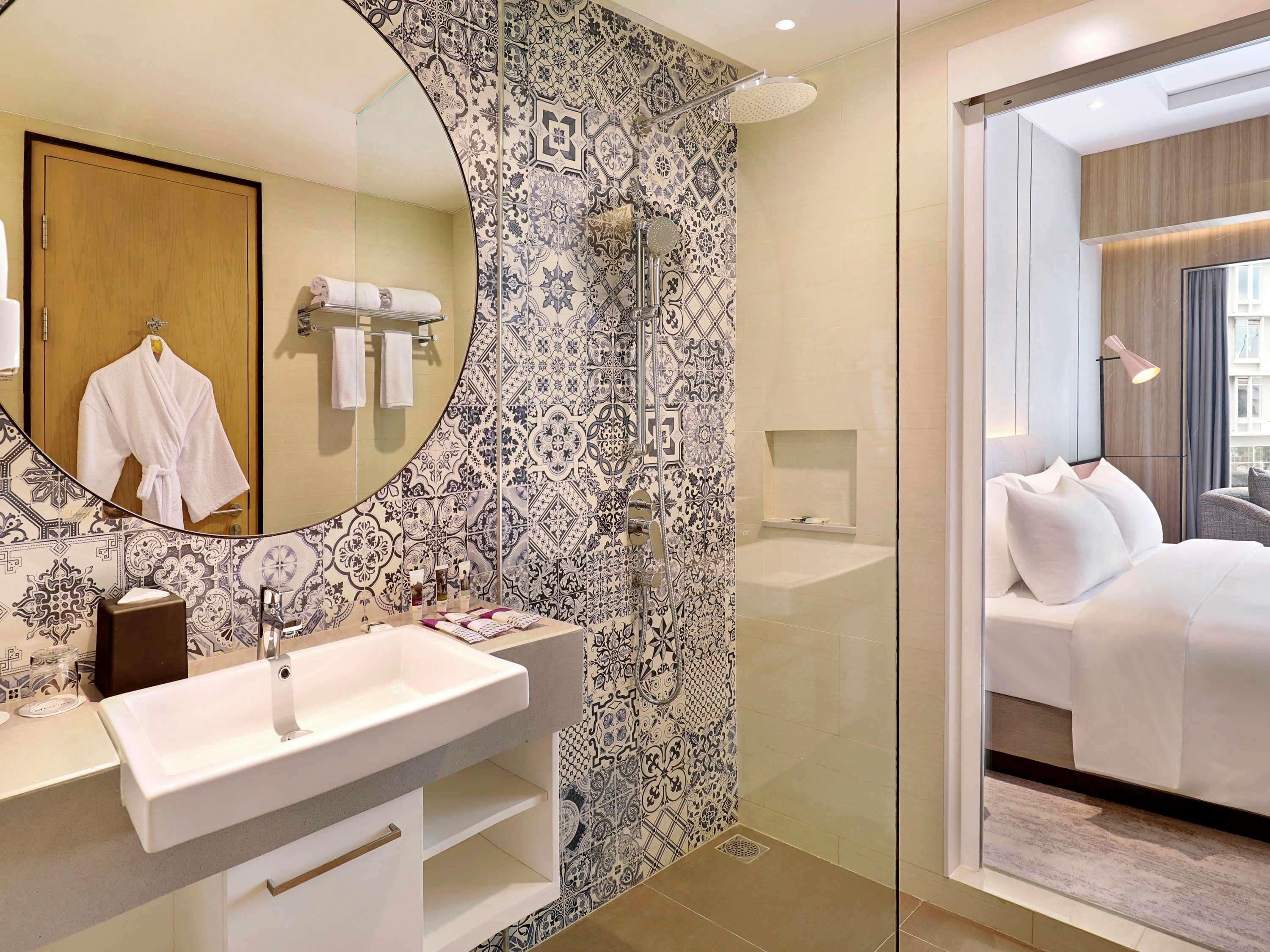A modern bathroom with a large mirror, a white sink, and a shower area.