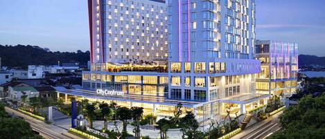 A modern hotel with multiple floors, a rooftop garden, and a view of the surrounding cityscape.