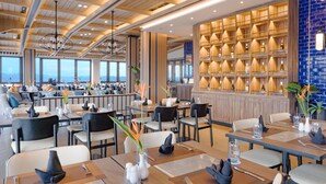 Un restaurante moderno con vigas de madera en el techo, una zona de bar con estanterías para vinos y vistas a la ciudad.