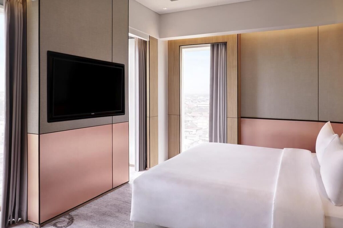 Una habitación de hotel moderna con una cama grande, un televisor de pantalla plana y vistas a la ciudad.