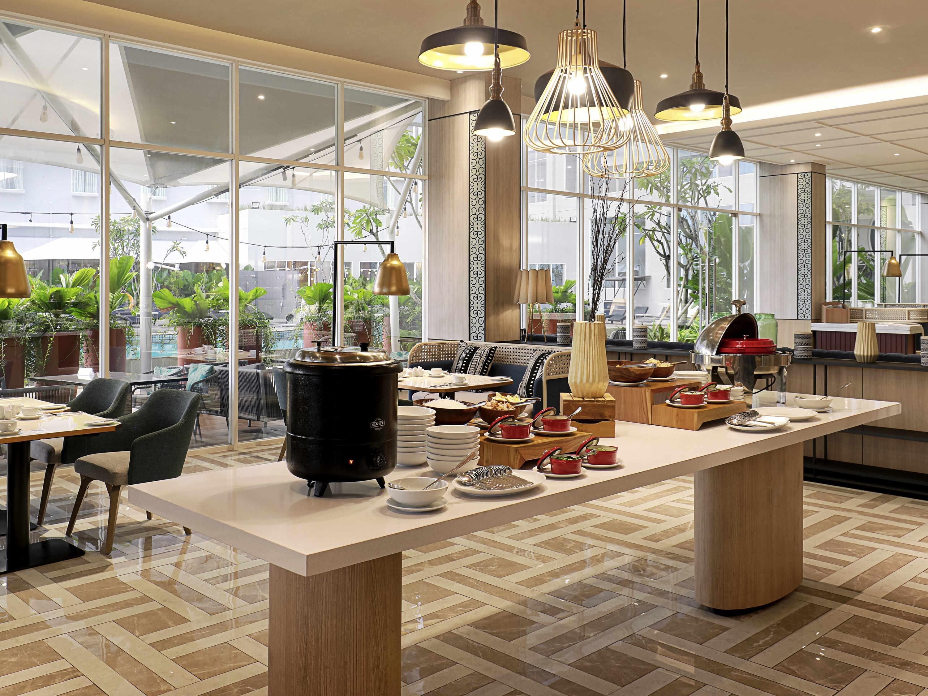 A modern restaurant with a central island, large windows, and a variety of seating options.