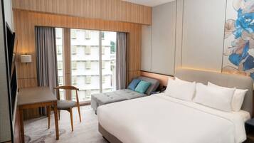 A hotel room with a bed, a desk, and a chair.