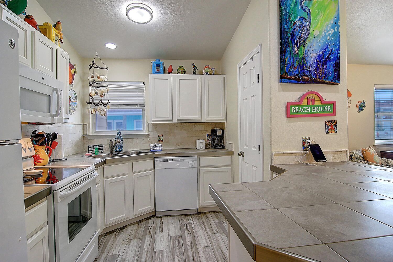 A kitchen with white cabinets, a dishwasher, and a dining area with a table.