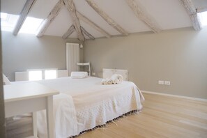 A bedroom with a large bed, a bedside table, a radiator, and a window. - Piazza dei Tribunali (Bologna)