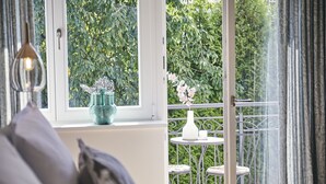 A room with a view of a balcony, a white vase with flowers, and a table with chairs. - BUITERLING Hotel (Brilon)