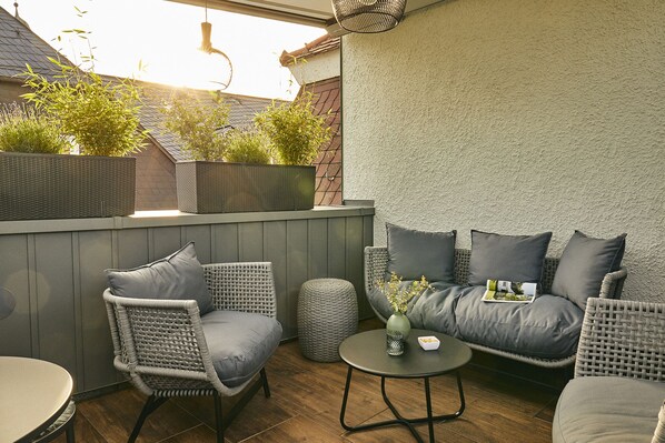 A patio area with wicker furniture, a round table, and a cushioned sofa.