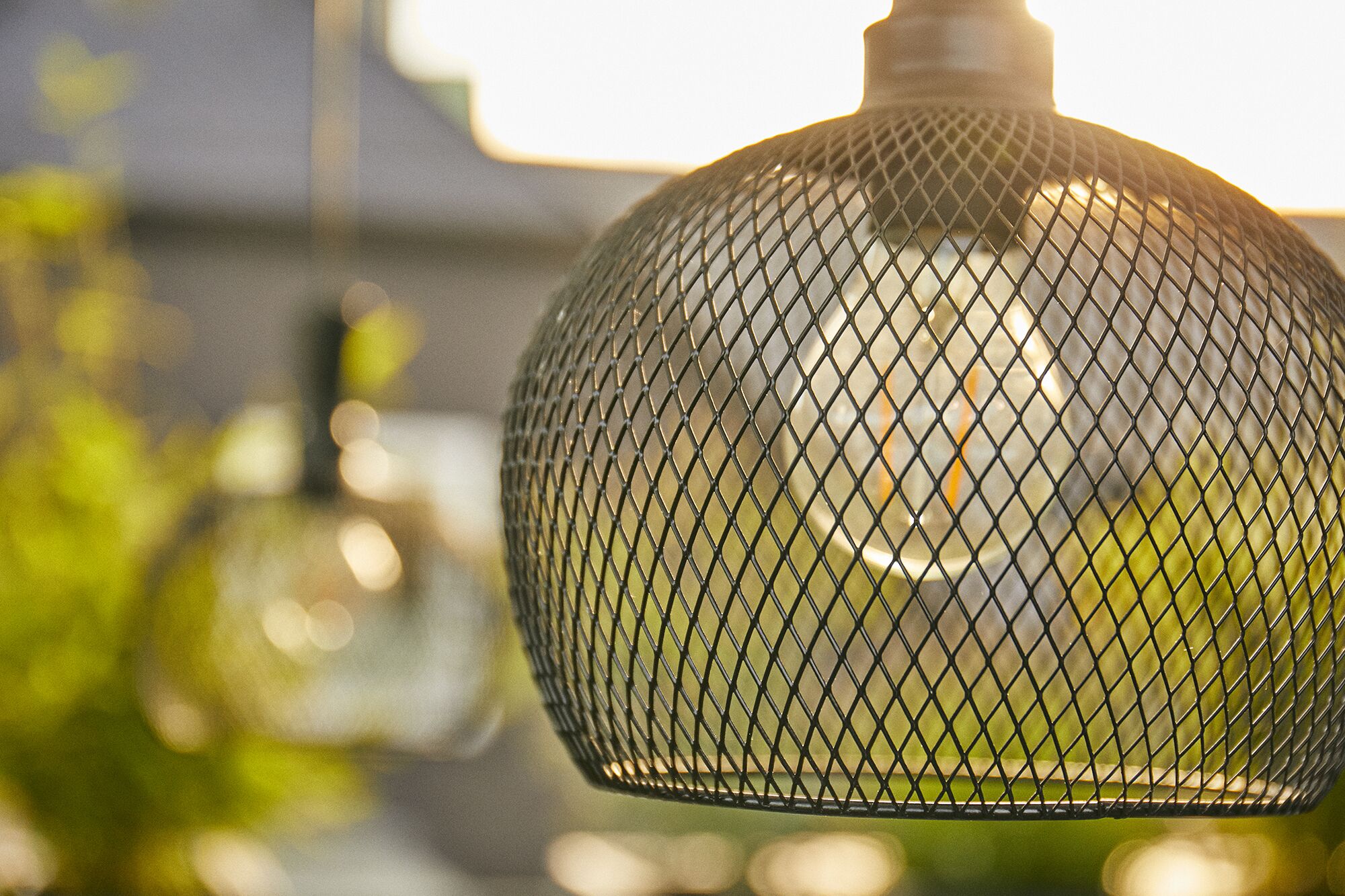 A close-up of a metal mesh light fixture with a spherical shape.