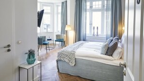 A bedroom with a large bed, a desk, a chair, and a window with curtains. - BUITERLING Hotel (Brilon)