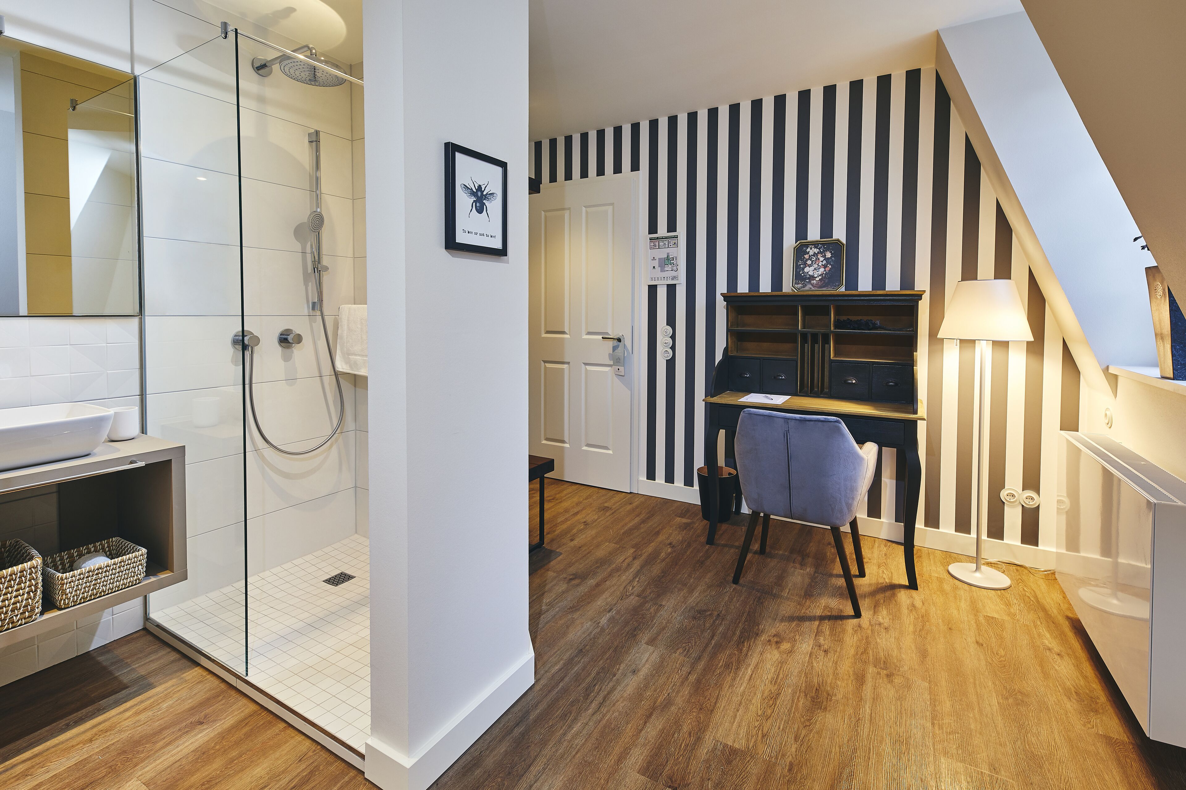 A modern bathroom with a glass shower enclosure, a white sink, and a wooden floor.