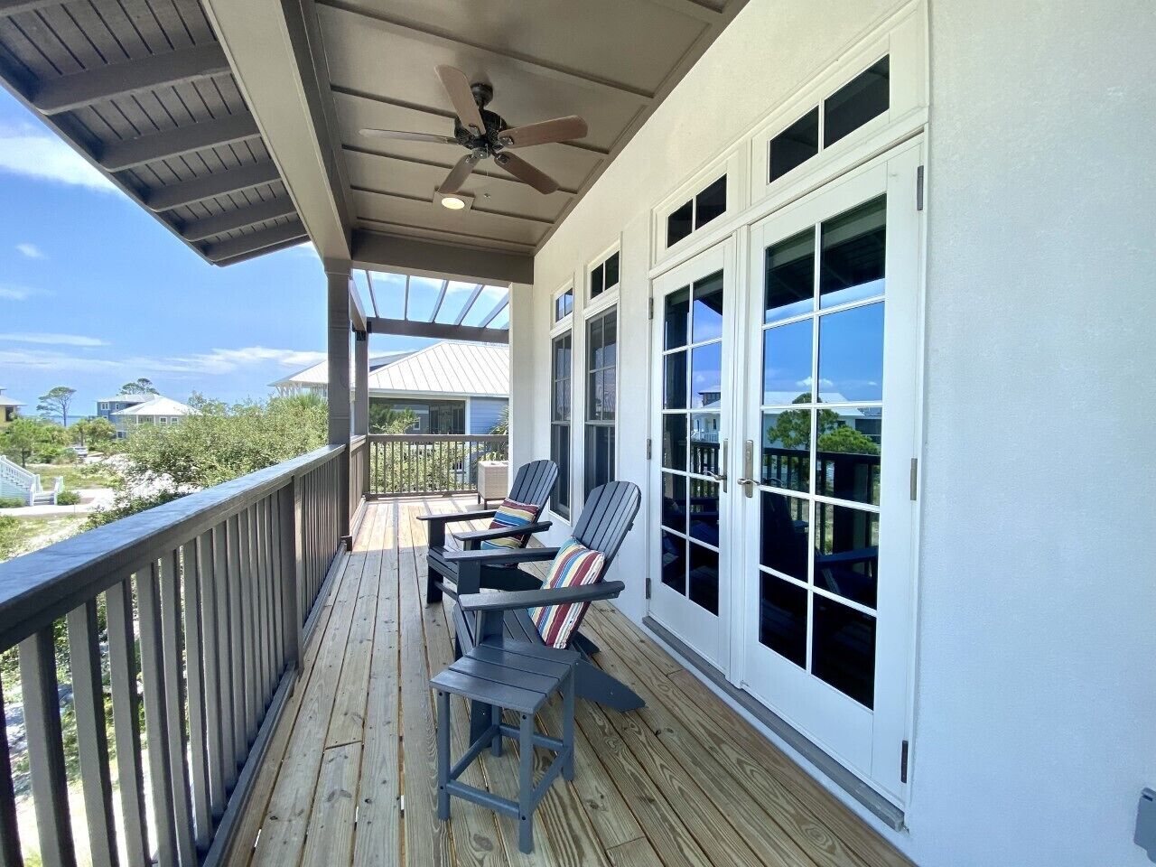 A covered outdoor deck with a ceiling fan, two chairs, and a table.