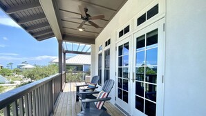 Terraza exterior cubierta con ventilador de techo, dos sillas y una mesa.