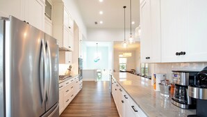 Una cocina moderna con electrodomésticos de acero inoxidable, armarios blancos y una encimera amplia.