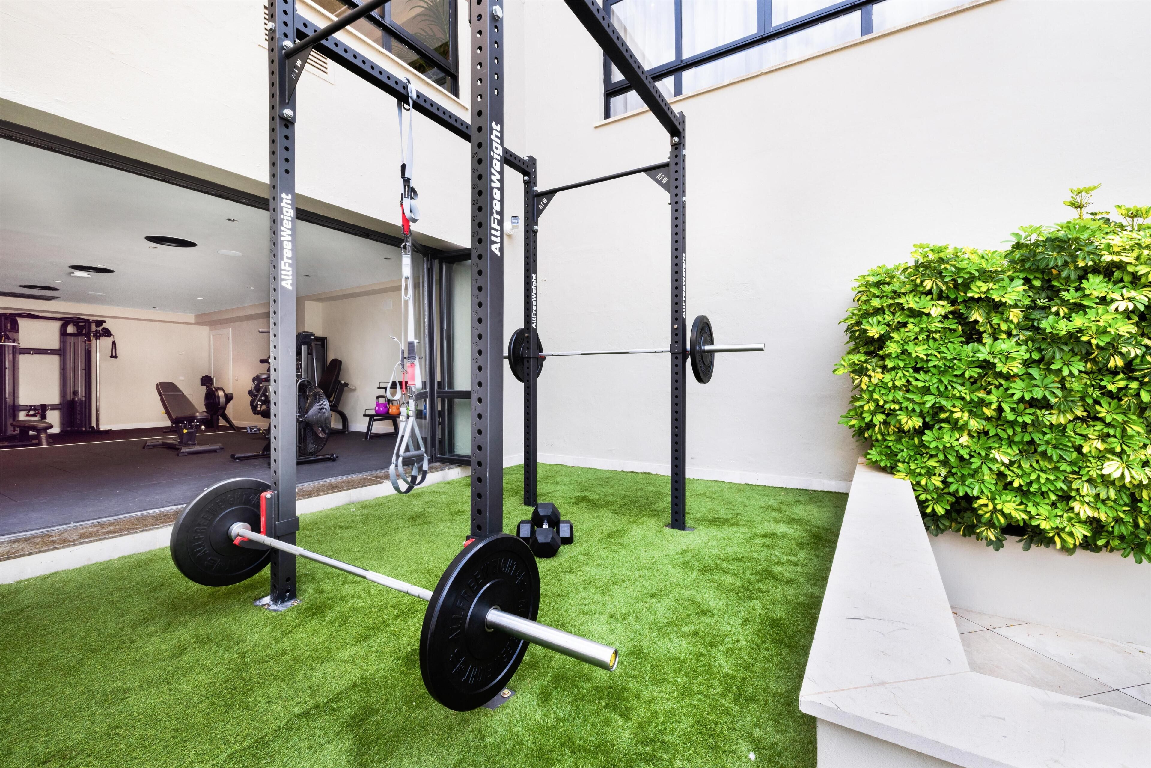 Un gimnasio con una zona de levantamiento de pesas, un espejo y un área de césped artificial verde.
