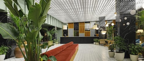 Un lobby moderno con un sofá rojo, plantas en macetas y un suelo estampado.