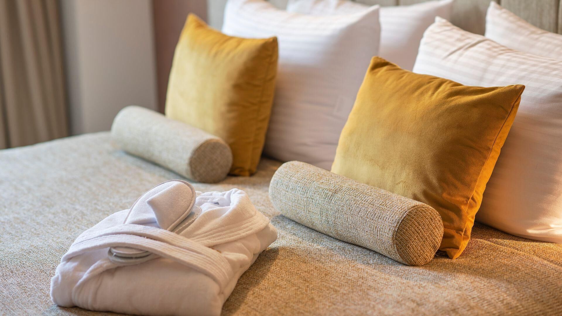 Un lit bien fait, avec des serviettes et des oreillers soigneusement disposés dans une chambre d’hôtel.