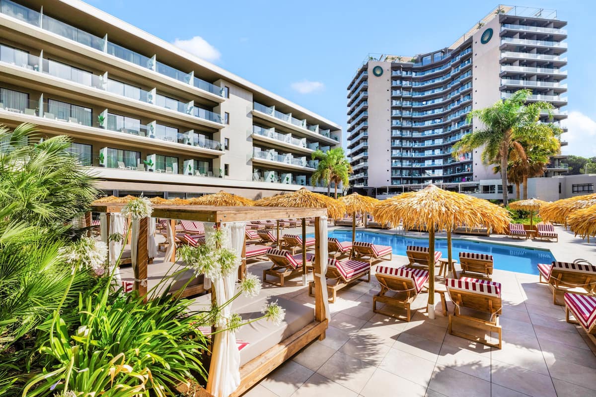 Un hotel con varios balcones, piscina y tumbonas.