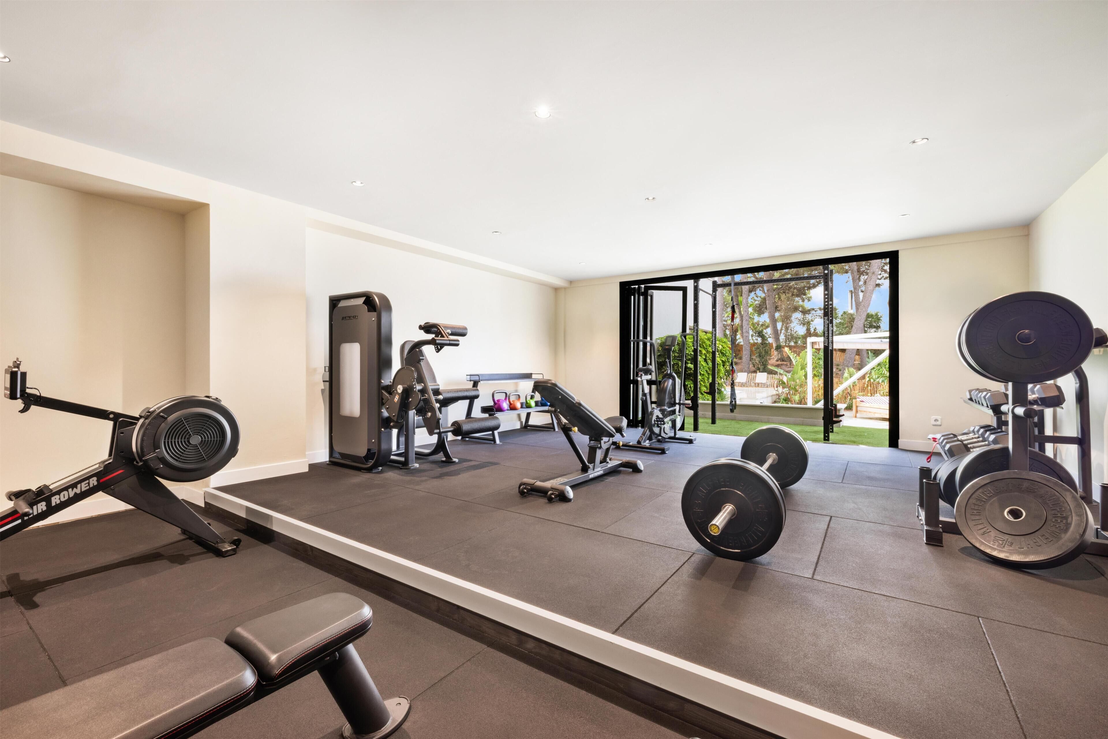 A modern gym with various exercise equipment, including a rowing machine, dumbbells, and weight benches.