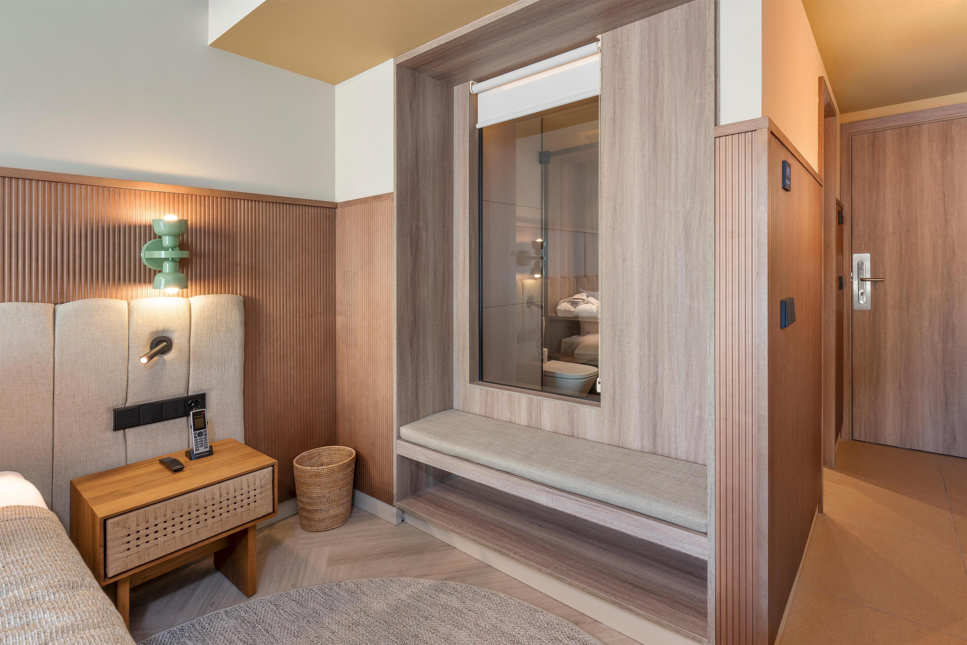 Un baño moderno con tocador de madera, ducha integrada y banco.