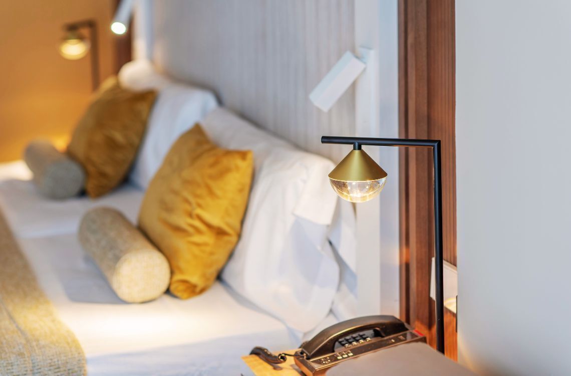 A hotel room with a bed, a bedside lamp, and a telephone.