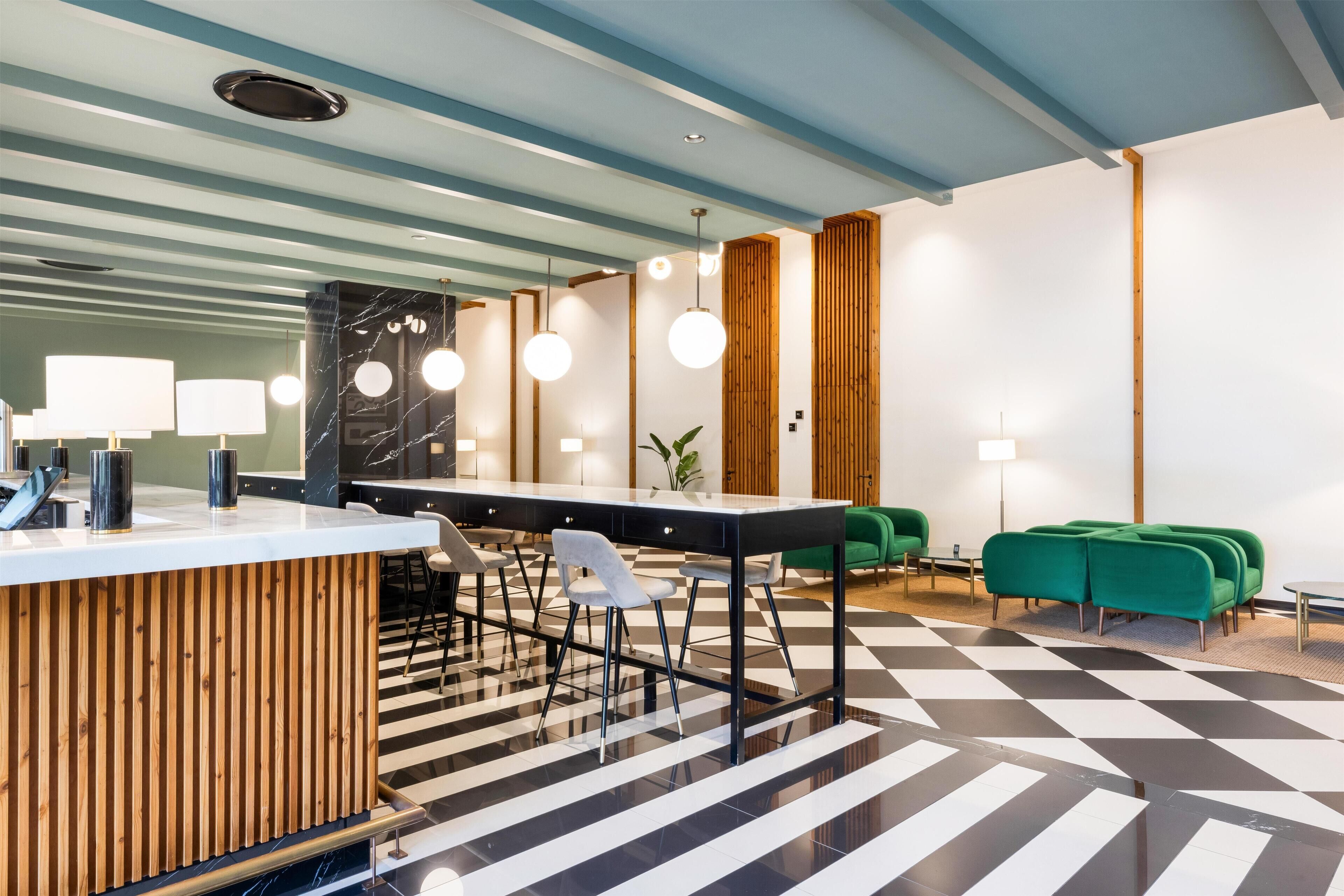 A modern reception area with a check-in counter, seating, and a checkered floor.