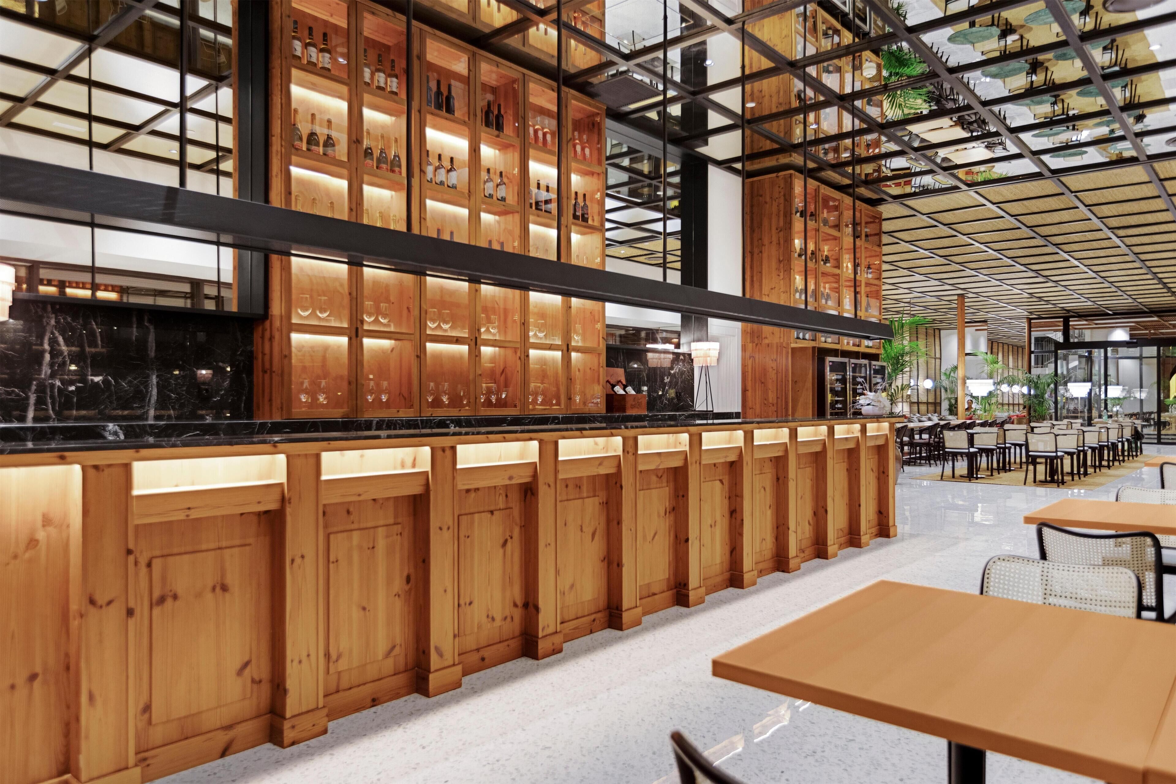 Un interior moderno con armarios de madera, una zona de bar y diferentes disposiciones de asientos.