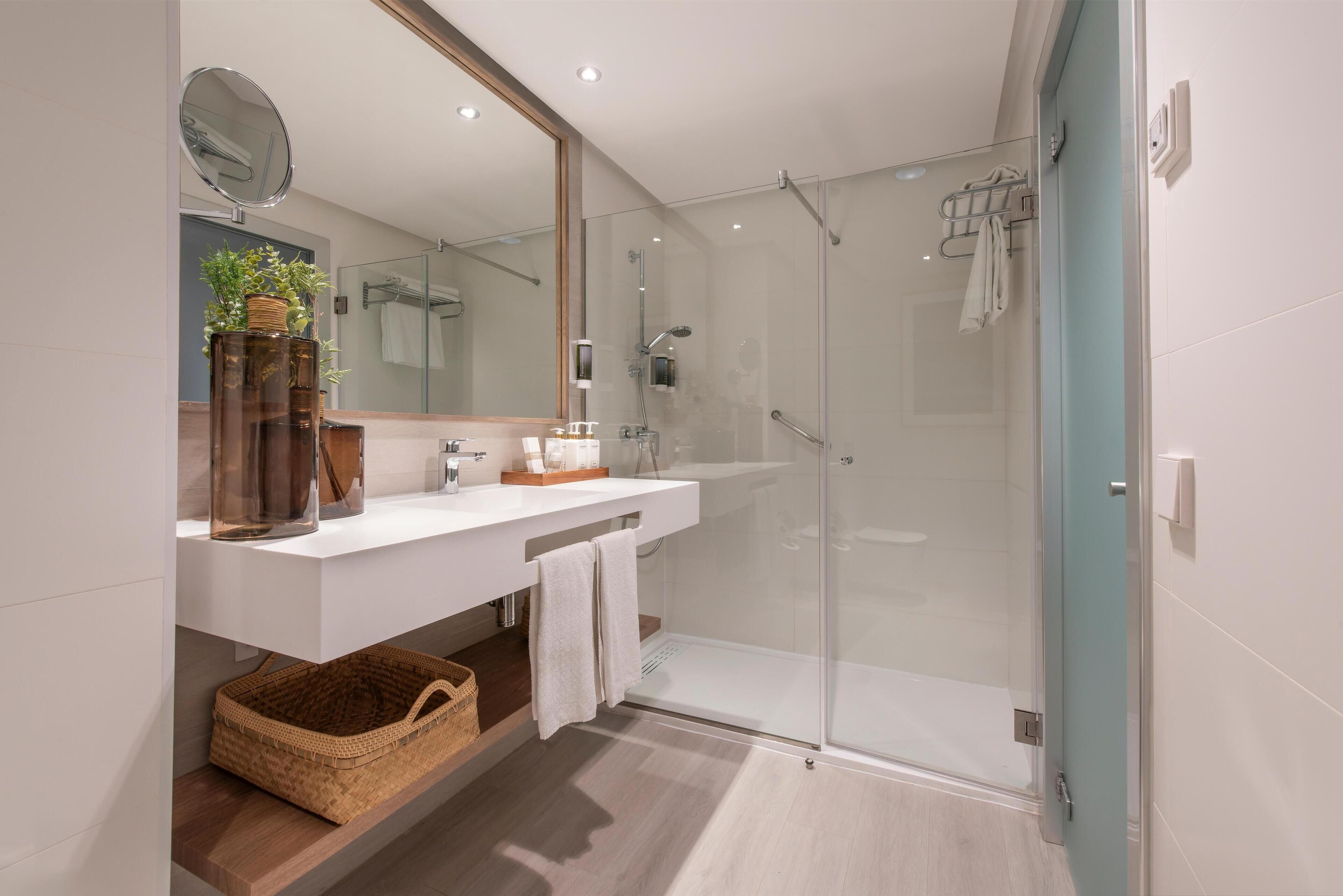 A modern bathroom with a glass-enclosed shower, a white vanity, and a large mirror.