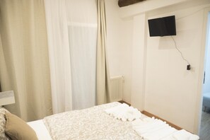 A hotel room with a bed, curtains, a wall-mounted TV, and a radiator. - Casa Bella Sunday (Bologna)