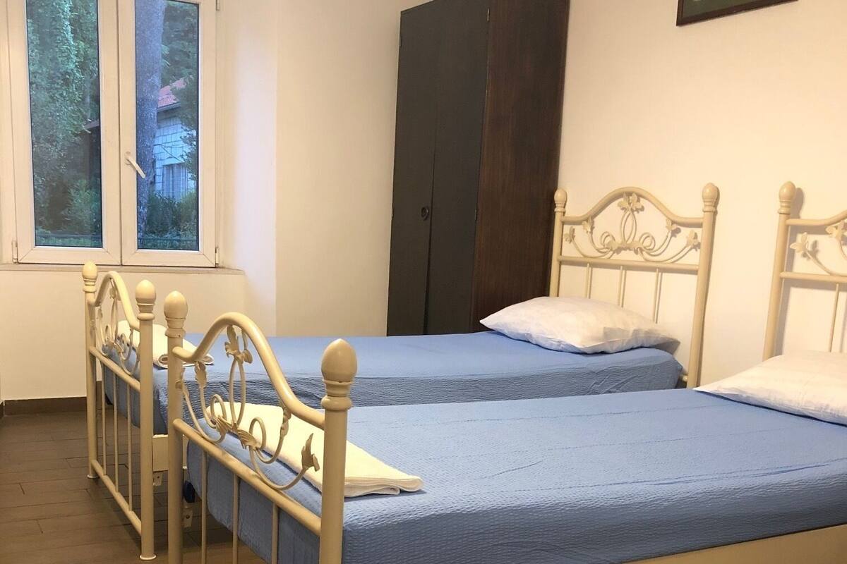 Makuuhuoneessa on kaksi sänkyä, vaatekaappi ja ikkuna, josta on näkymä puita kohti.