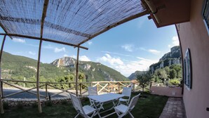 Un patio con mesa y sillas, vistas a montañas y una estructura de pérgola.