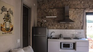 Una cocina compacta con pared de piedra, horno empotrado, microondas y fregadero.