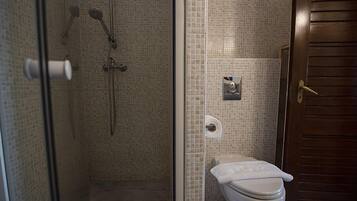 A bathroom with a glass-enclosed shower, a toilet, and a towel rack.