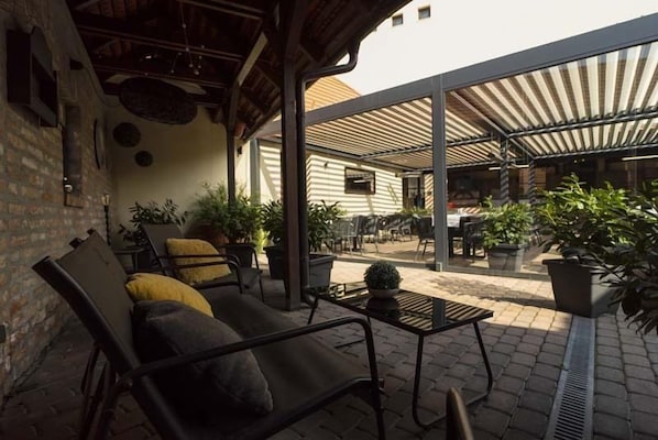 Un espacio al aire libre con patio, sofá, sillas y plantas en macetas.
