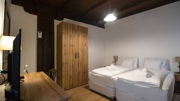 A bedroom with a wooden desk, two beds, and a wardrobe.