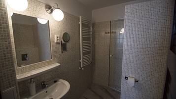 Un baño con lavamanos, espejo y ducha.