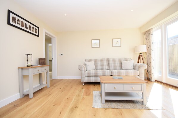 A living room with a sofa, coffee table, and a framed picture on the wall. - The Parlour , Emsworth - a barn conversion that sleeps 6 guests in 3 bedrooms (Emsworth)