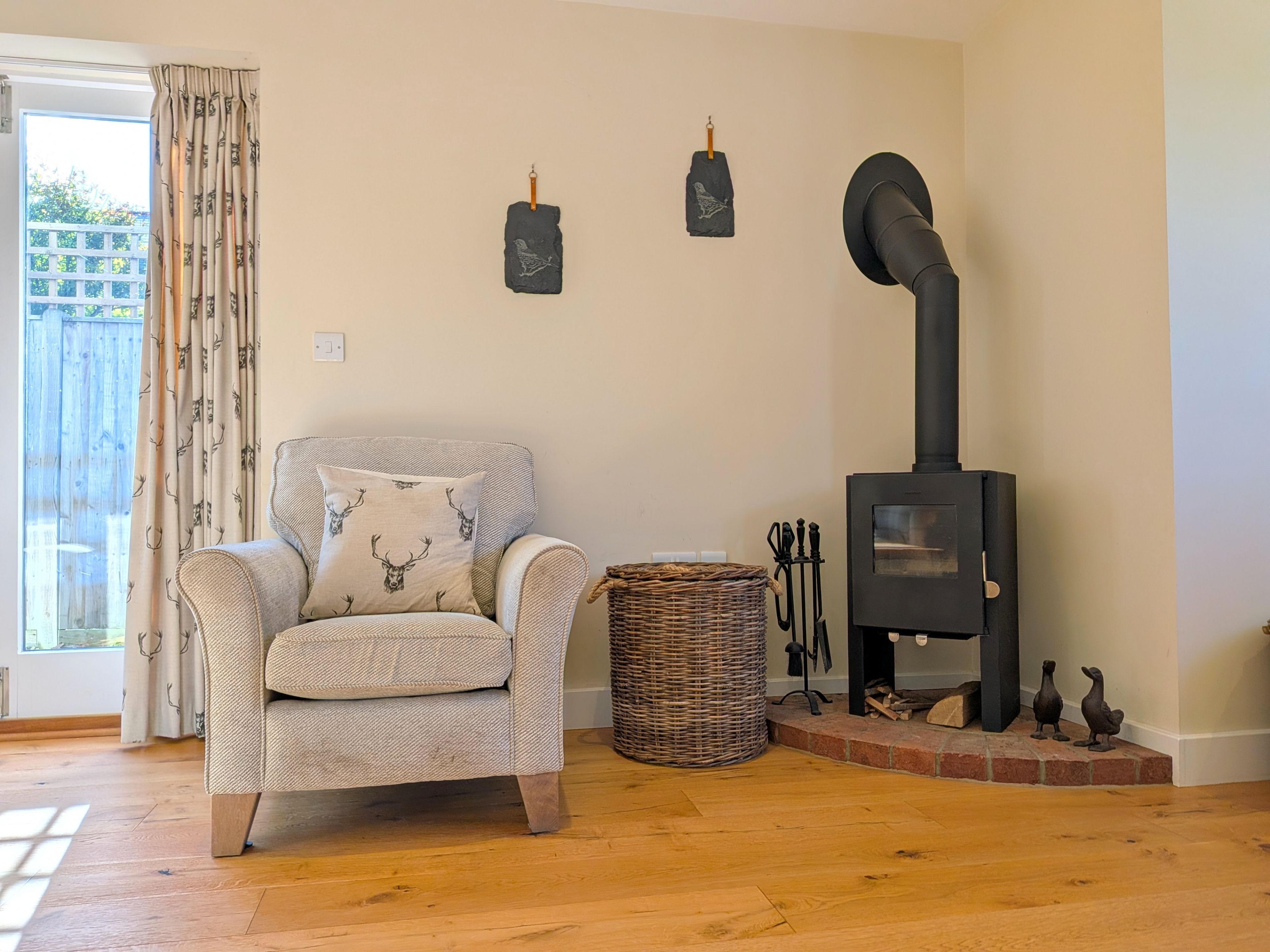 A cozy room with a fireplace, a wicker basket, and a chair with a deer-patterned cushion.
