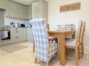 A kitchen with light-colored cabinets, a dining table with chairs, and a painting on the wall.
