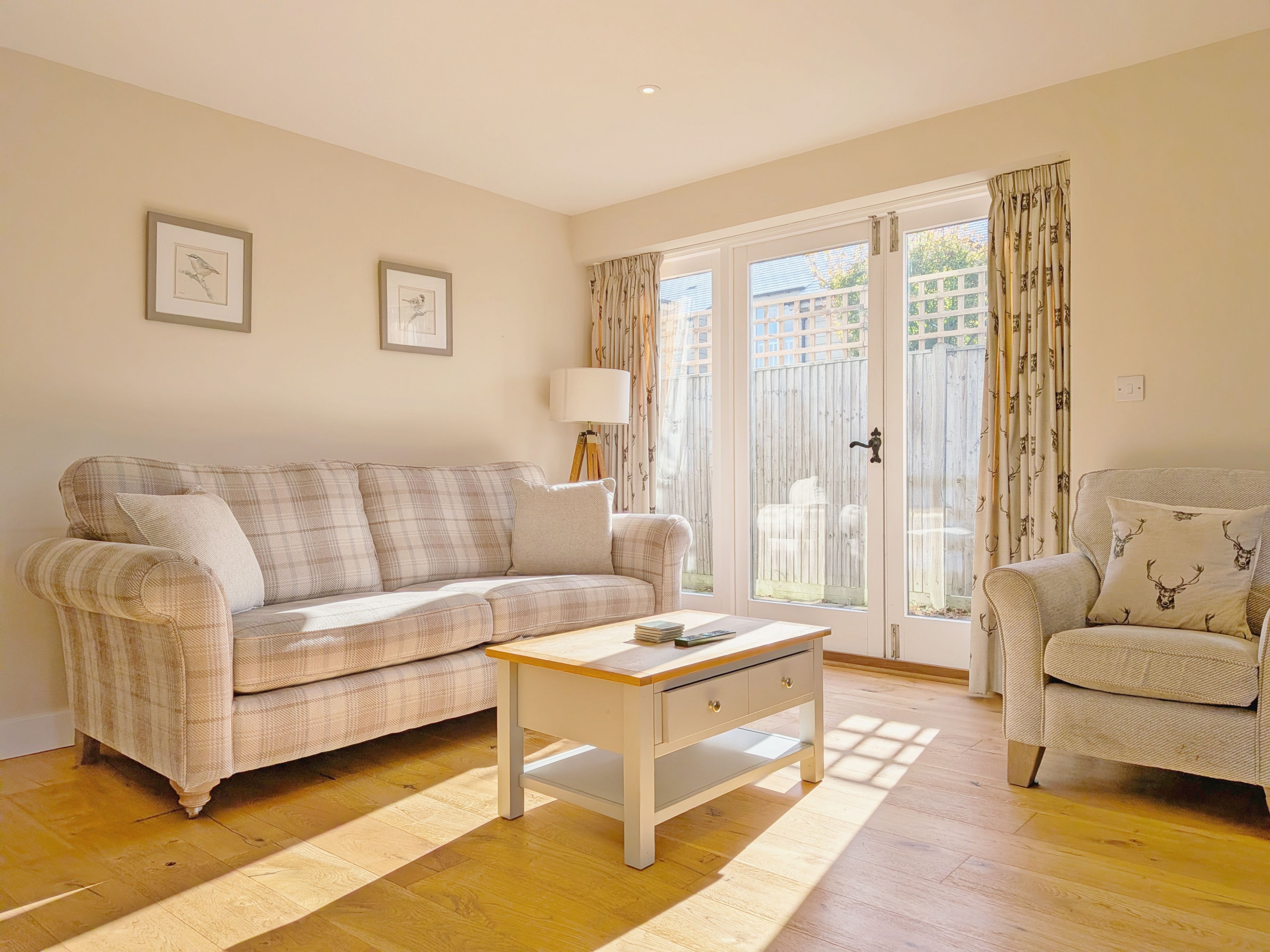 Un salon comprenant un canapé, une table basse, un fauteuil et une porte donnant sur un balcon.