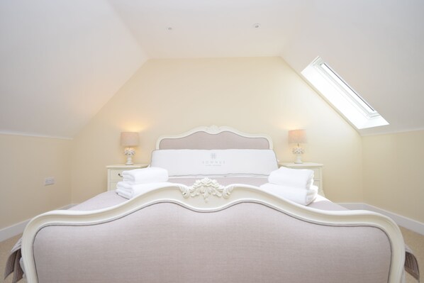 A bedroom with a large bed, two bedside lamps, a skylight, and a nightstand with a lamp. - The Dairy , Emsworth - a barn conversion that sleeps 4 guests in 2 bedrooms (Emsworth)