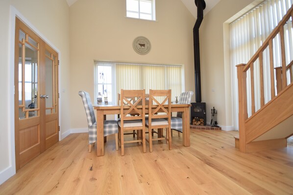 A dining area with a wooden table and chairs, a fireplace, and a staircase.
