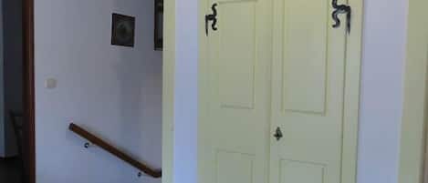 A hallway with a light green door, a wooden handrail, and a small picture on the wall.