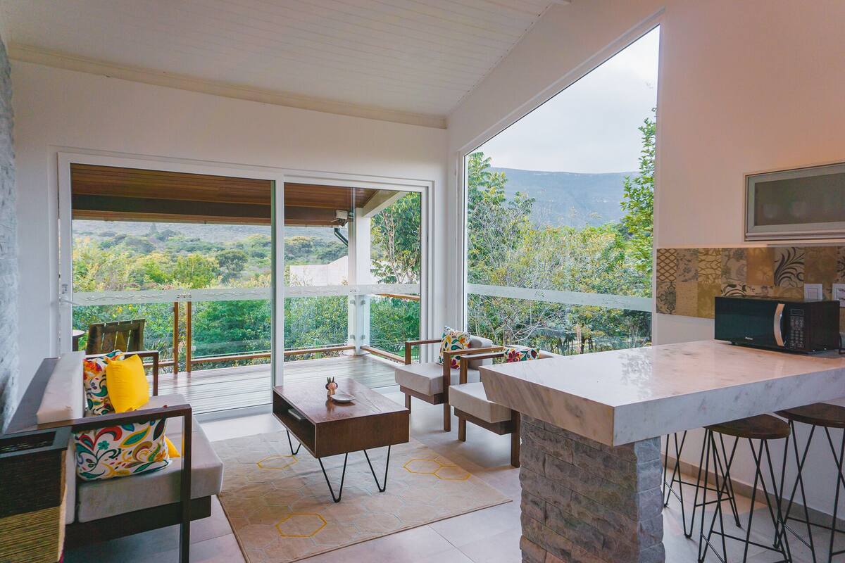 Eine moderne Küche mit einer großen Kochinsel, Barhocker und Blick auf eine Berglandschaft.