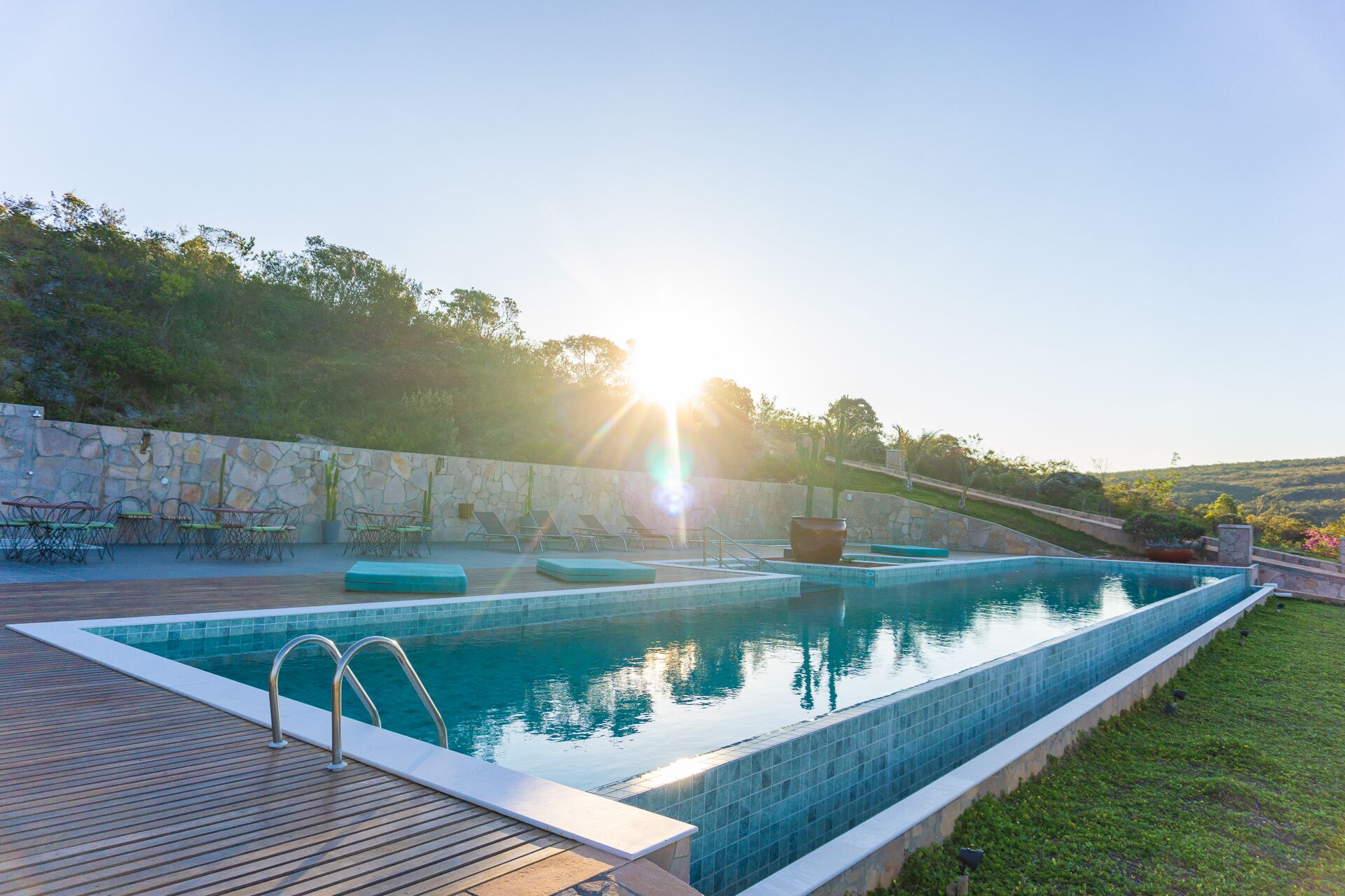 Et rektangulært pool med en stenvæg og en træterrasse.