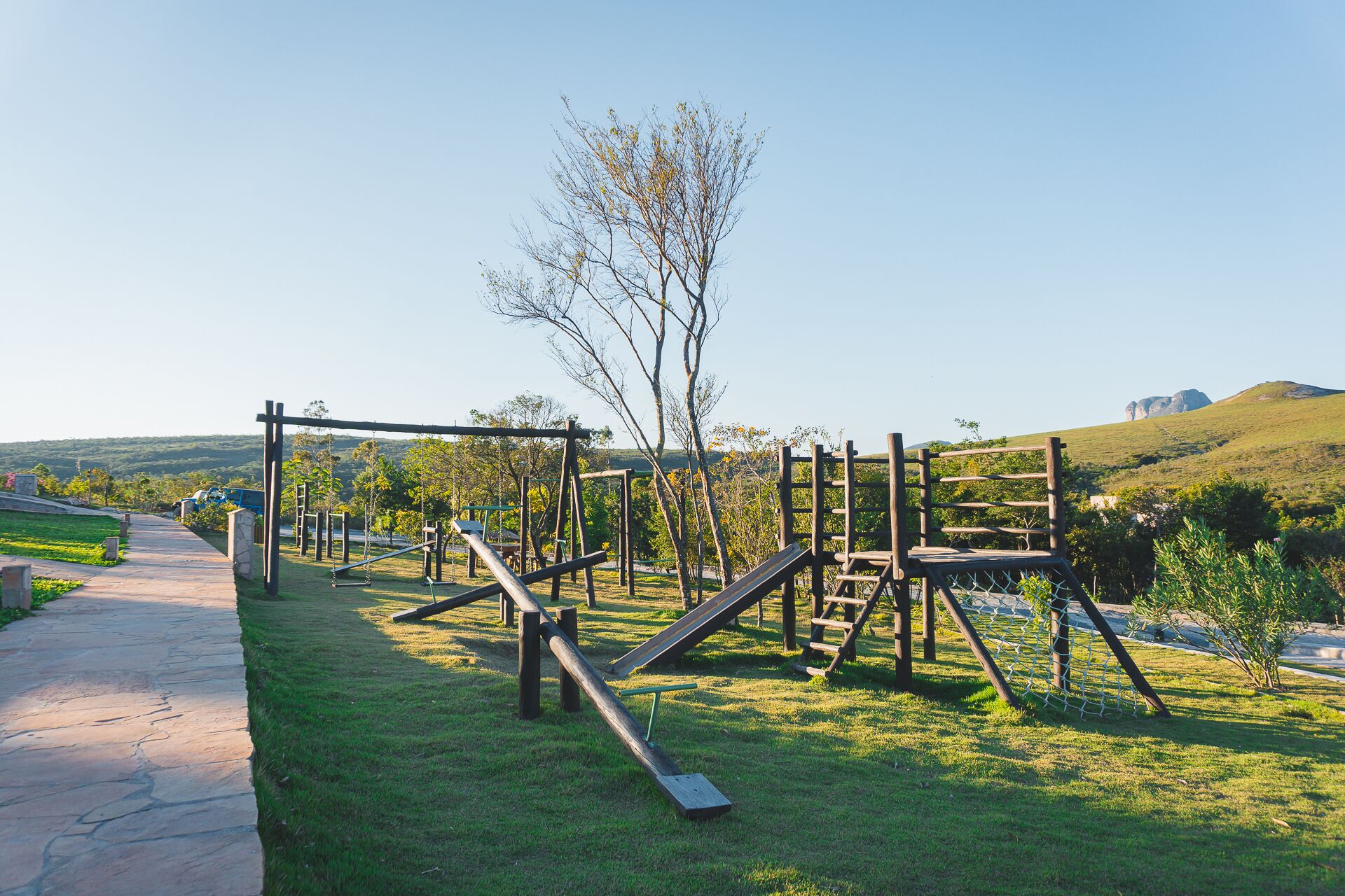 Un patio de juegos al aire libre con diversas estructuras de madera y un sendero pavimentado.