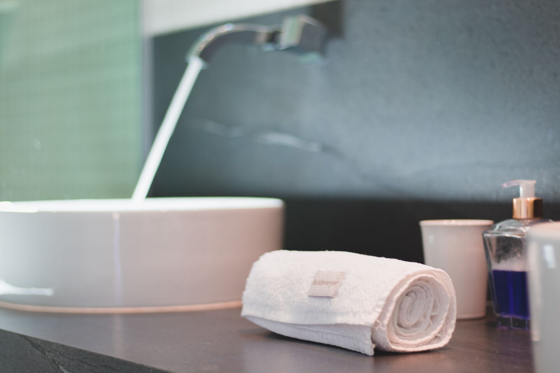 A bathroom with a white sink, a towel, and a bottle of soap.