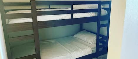 A bunk bed with a ladder, a single bed, and a small window.