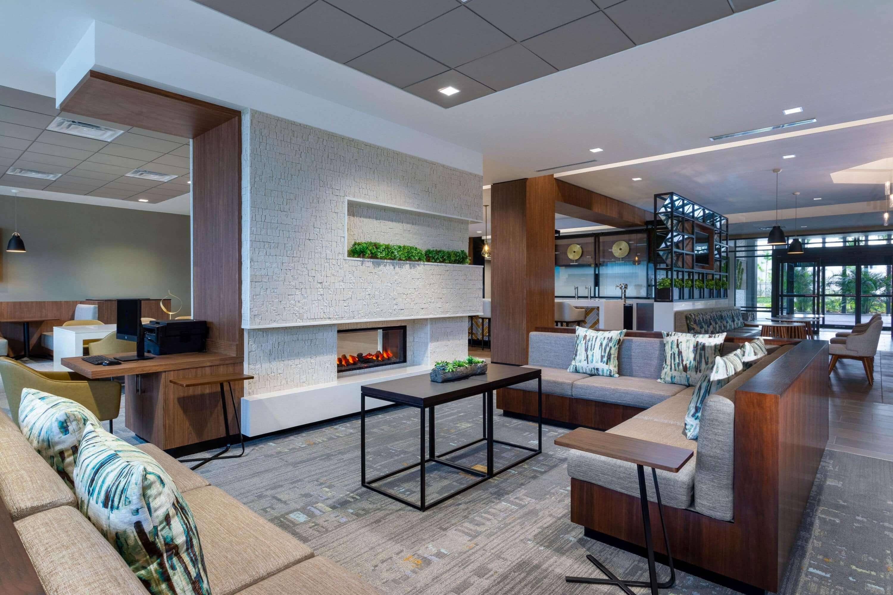 A modern lobby with a fireplace, seating area, and a bar.
