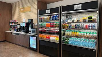 A self-service beverage station with refrigerated drink dispensers and a coffee machine.